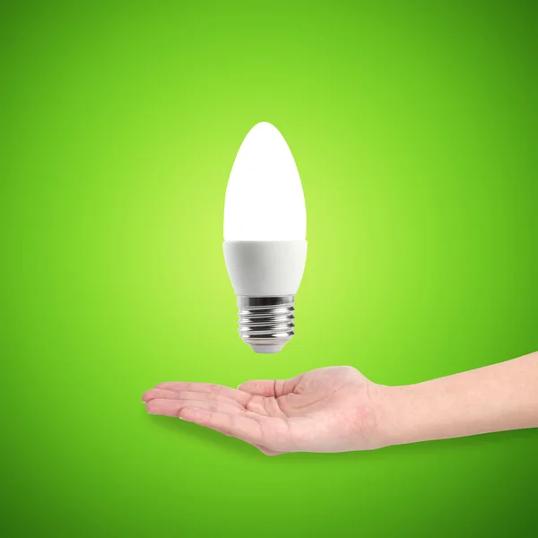 Светящиеся Светодиодные энергосберегающие лампы в руке на зеленом фоне — стоковое фото